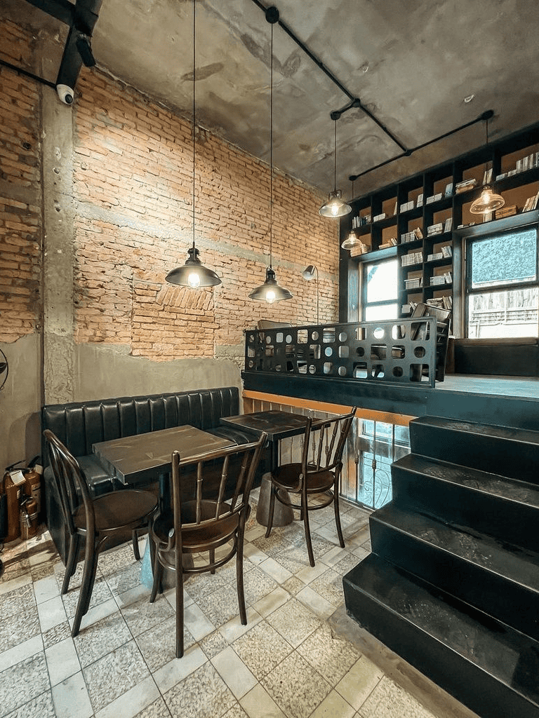 Cozy coffee shop interior with exposed brick walls, modern lighting, and a comfortable seating area.