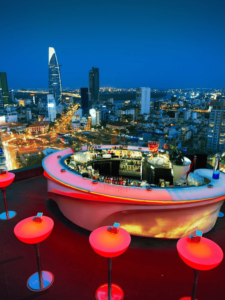Modern rooftop bar with city skyline views and vibrant lighting in downtown.