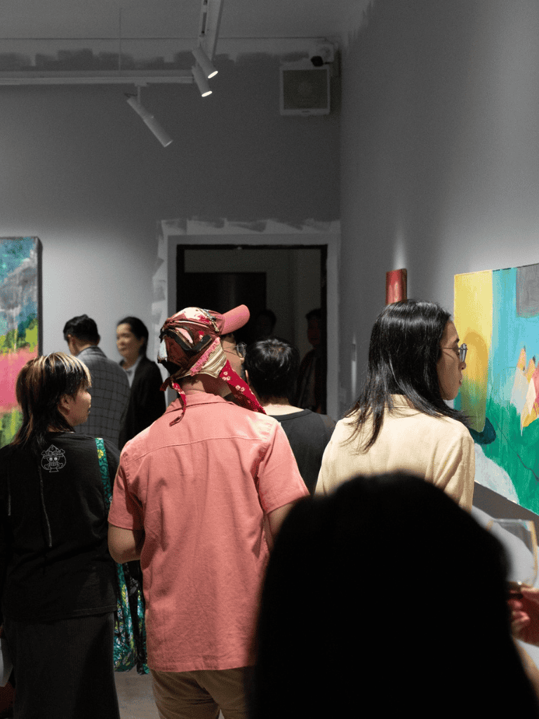 Colorful art exhibit at QuestForDirections - diverse crowd enjoying artwork in a gallery space.