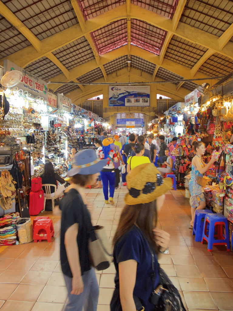 Colorful indoor market in Vietnam with shoppers exploring local goods and souvenirs.