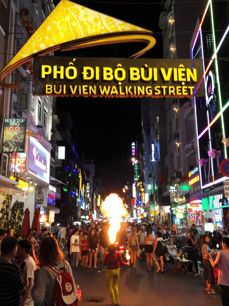 Vibrant Bui Vien Walking Street at night, bustling with people, colorful neon signs, and lively nightlife in Ho Chi Minh City.