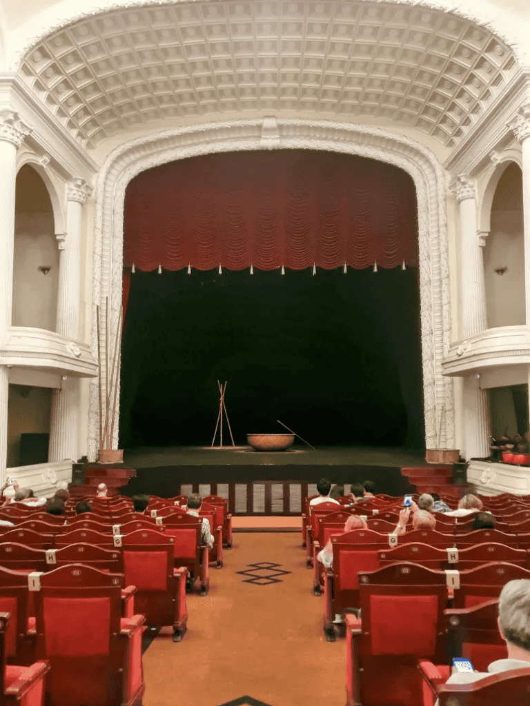 Historic theater stage with red velvet curtains and ornate architecture for cultural events.