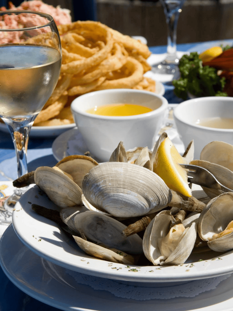 Freshly cooked oysters with lemon wedges, served with fried calamari, dipping sauces, and a glass of white wine.