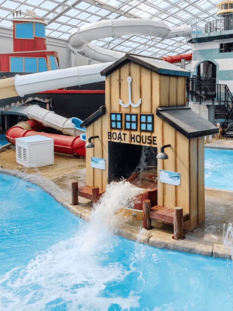 Colorful indoor water park with water slide and boat house attraction.