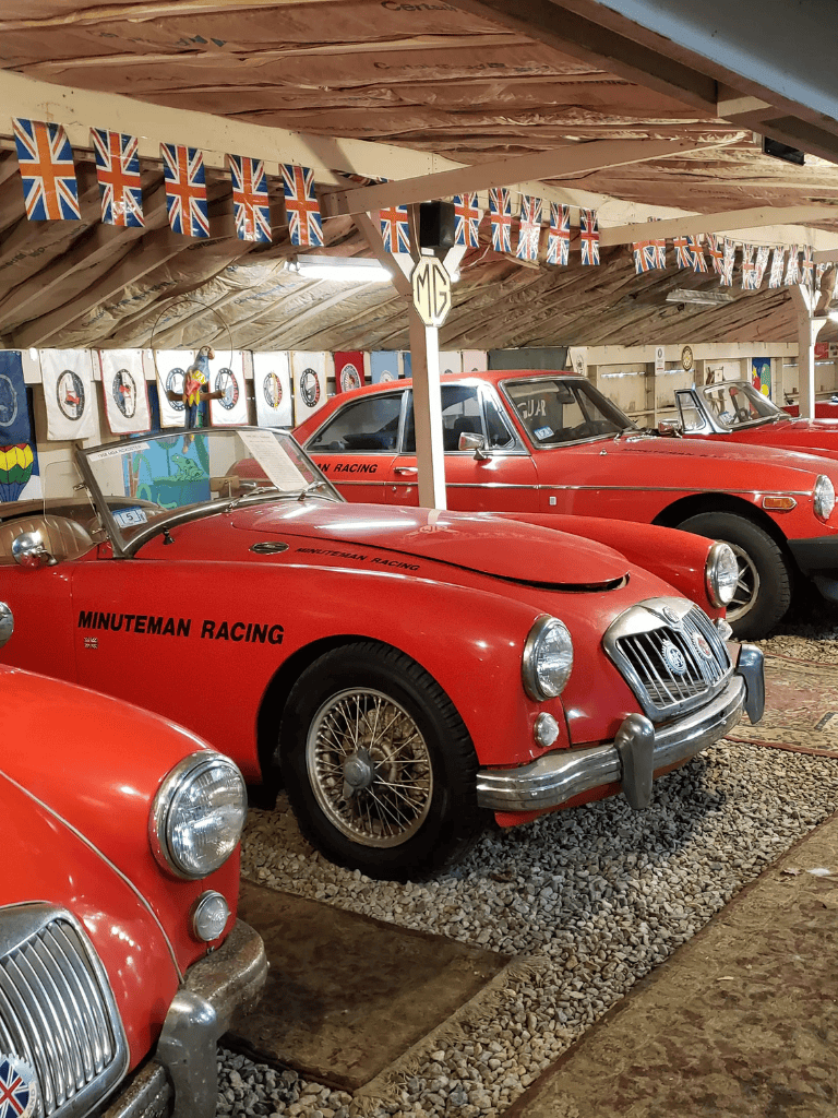 Vintage race cars at QuestForDirections museum for classic car enthusiasts, with British flags and racing memorabilia.