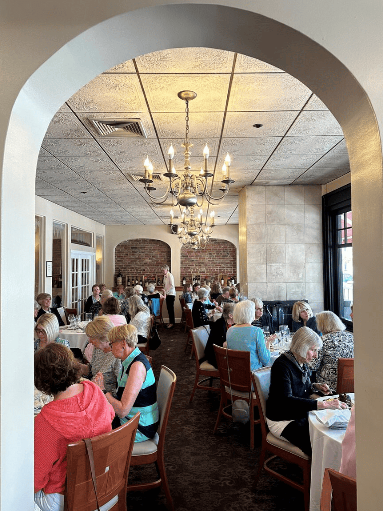 A cozy, elegant restaurant interior with senior guests dining, warm lighting, and brick accent wall.