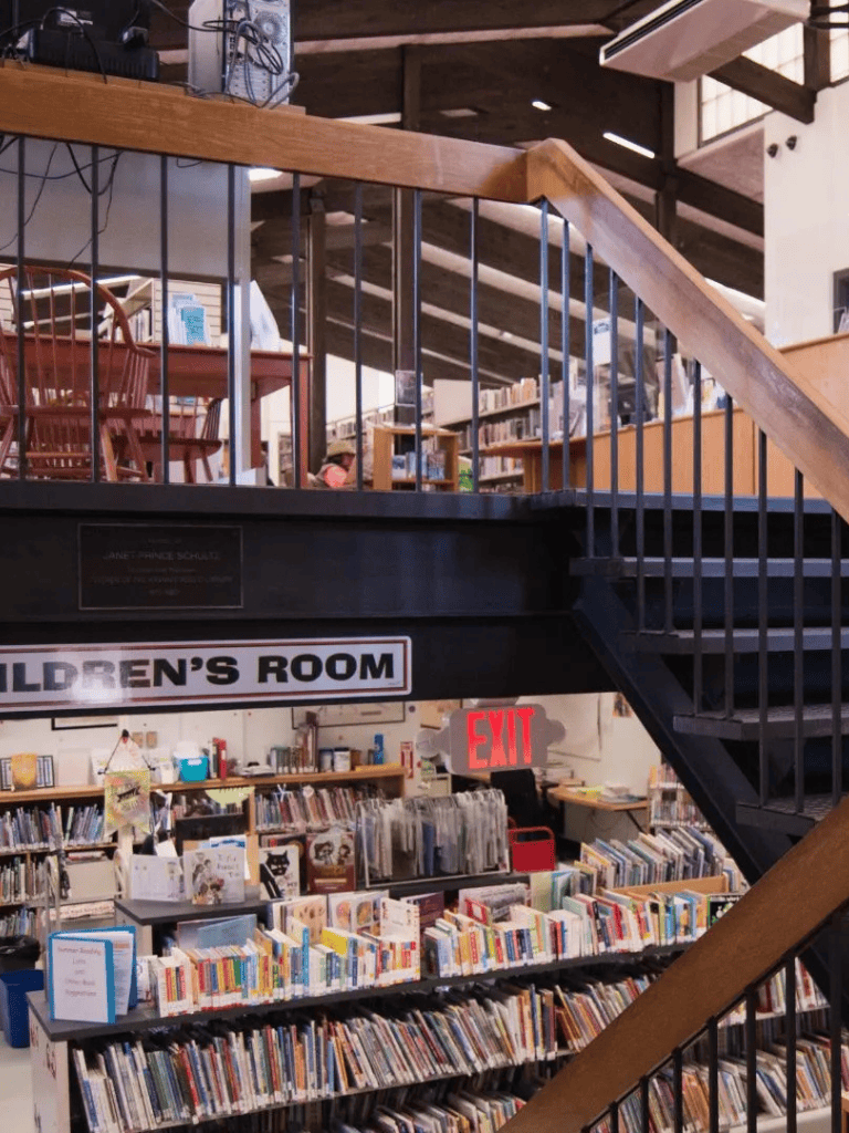 Library children's reading area with bookshelves and staircase for kids.