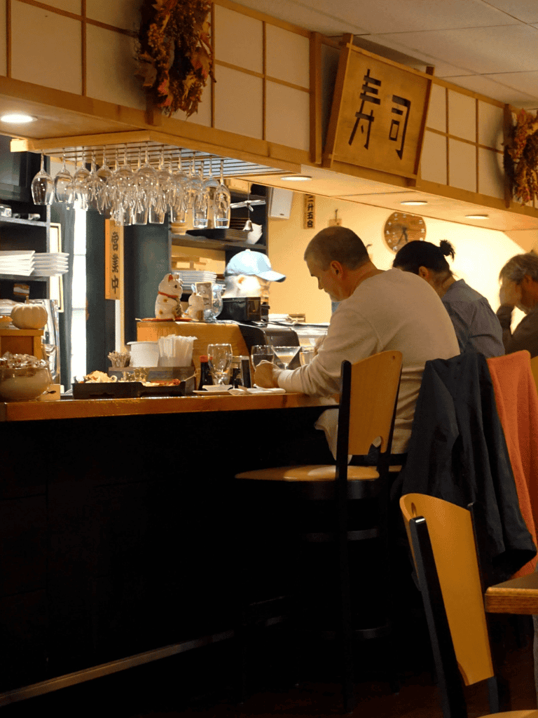 Cozy Japanese restaurant interior with diners at the bar, showcasing authentic ambiance and traditional decor.