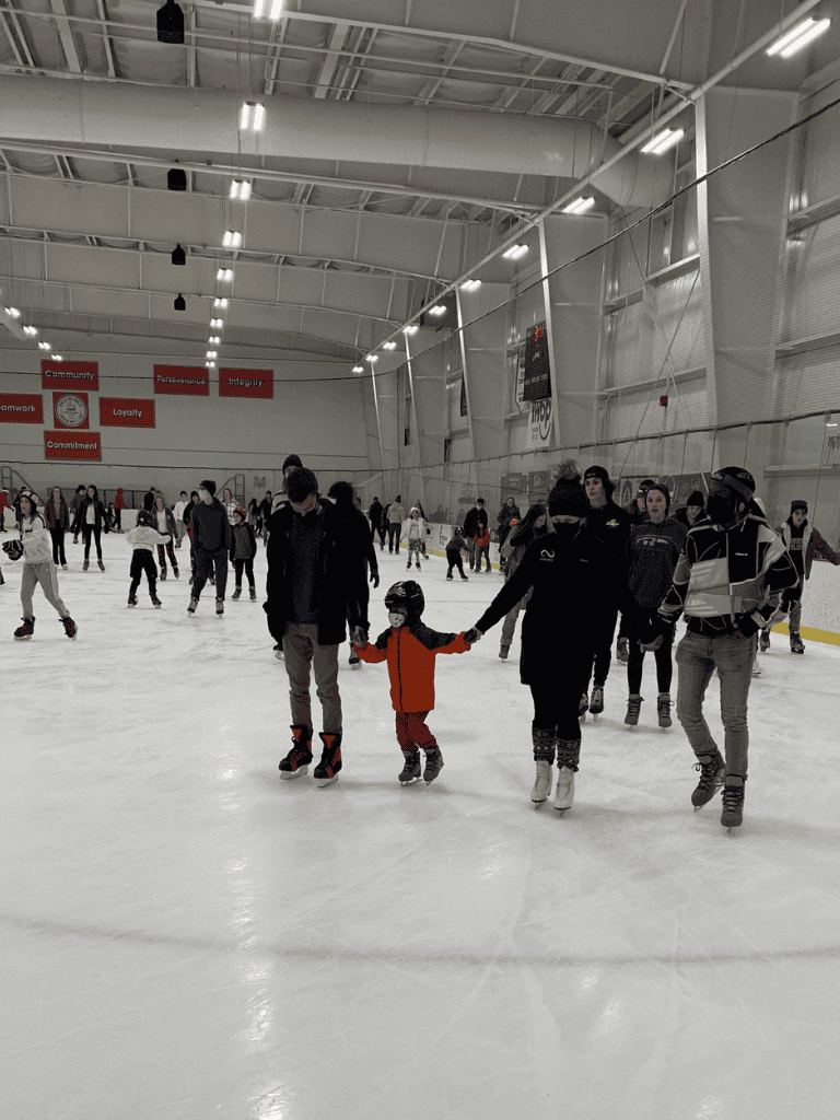 Indoor ice skating rink with families and children skating together, bright lighting, and high ceiling at QuestForDirections.