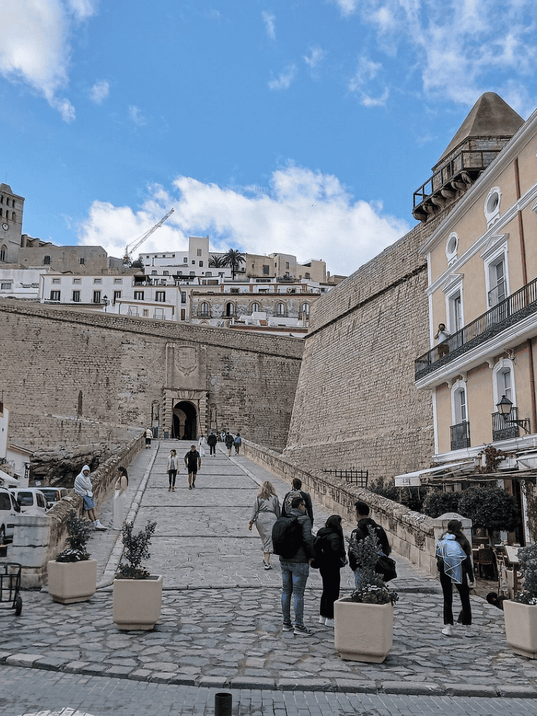 Ancient city wall with visitors, historic architecture, and a clear blue sky - perfect for travel guides.