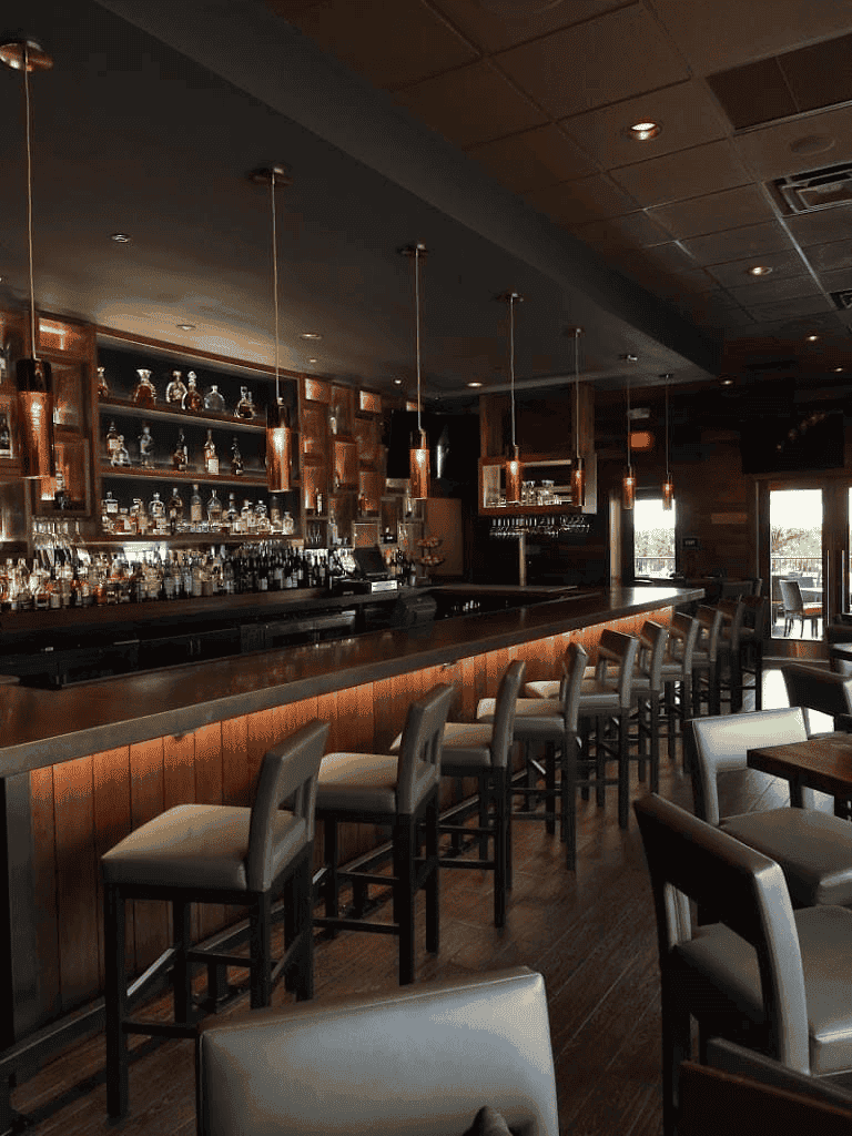 Cozy bar with wooden accents and modern lighting, ideal for relaxing and socializing.