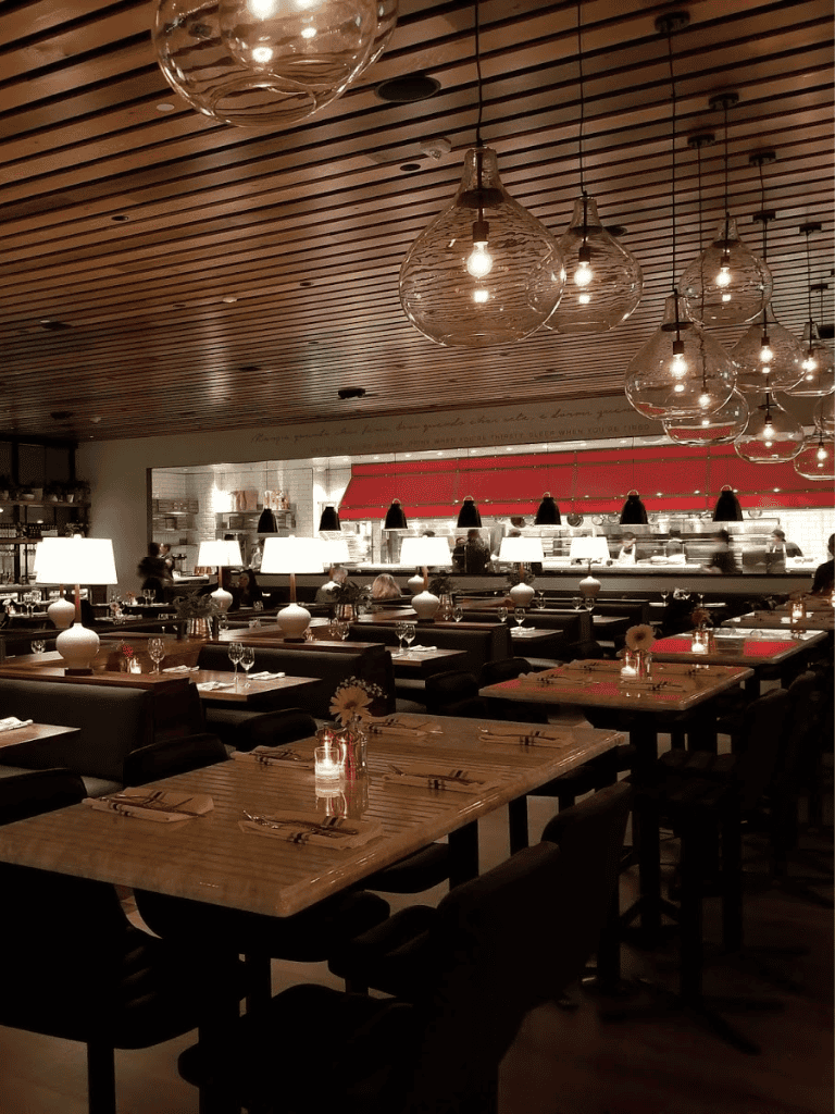 Cozy modern restaurant interior with dim lighting, pendant lights, and elegant table settings for fine dining experiences.