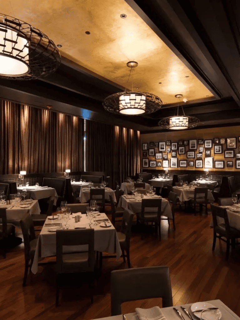 Elegant fine dining restaurant interior with dim lighting, customized table settings, and cozy warm ambiance.