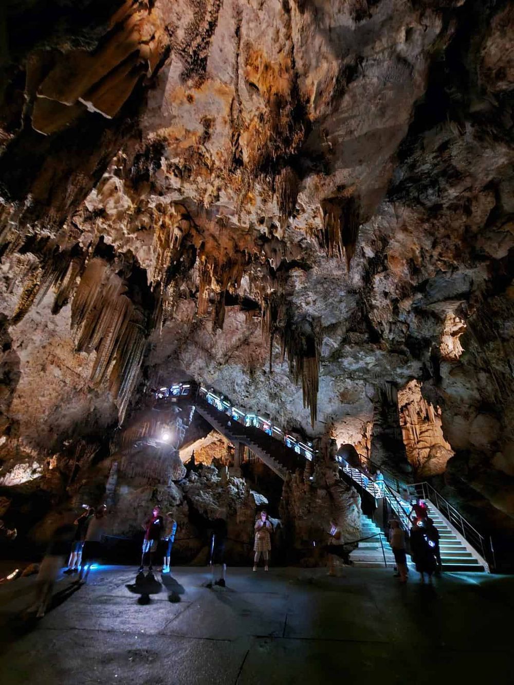 Vast limestone cave with stalactites and stalagmites, illuminated for visitors exploring underground formations.