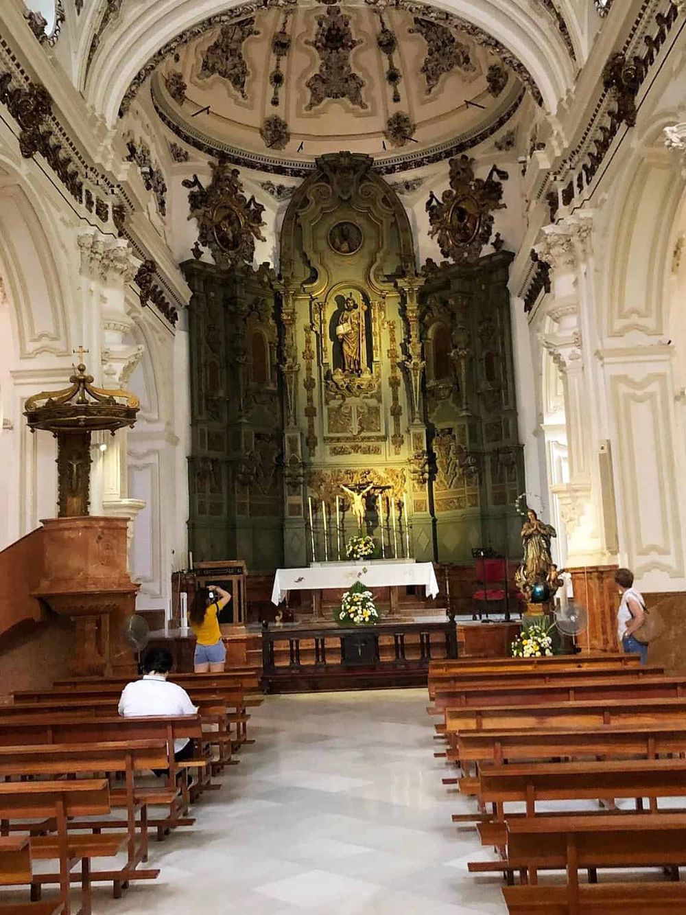 Intricate baroque church interior with altar, statues, and ornate ceiling decorations, perfect for religious tourism and cultural exploration.
