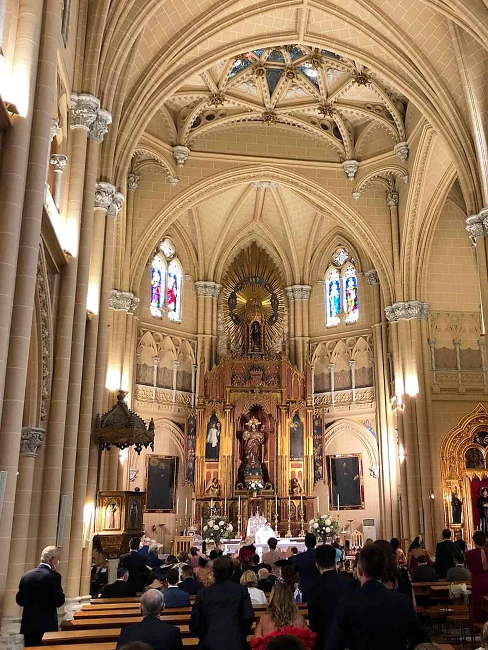 Elegant Gothic church interior with ornate altar and stained glass windows showcasing architectural beauty.