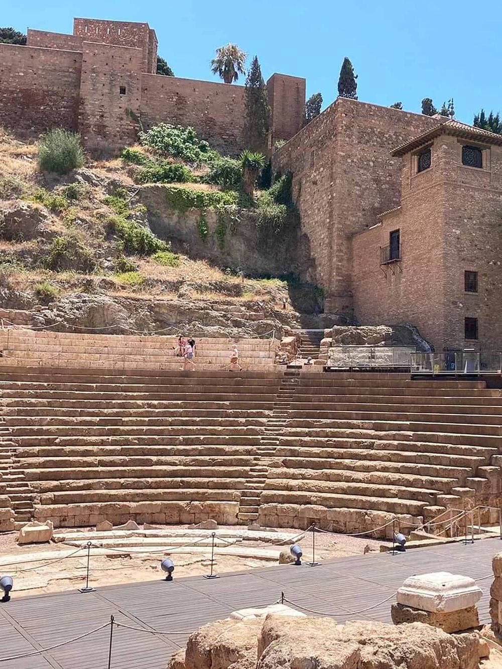 Ancient Greek theater with stone seating and historic ruins in a scenic outdoor setting.