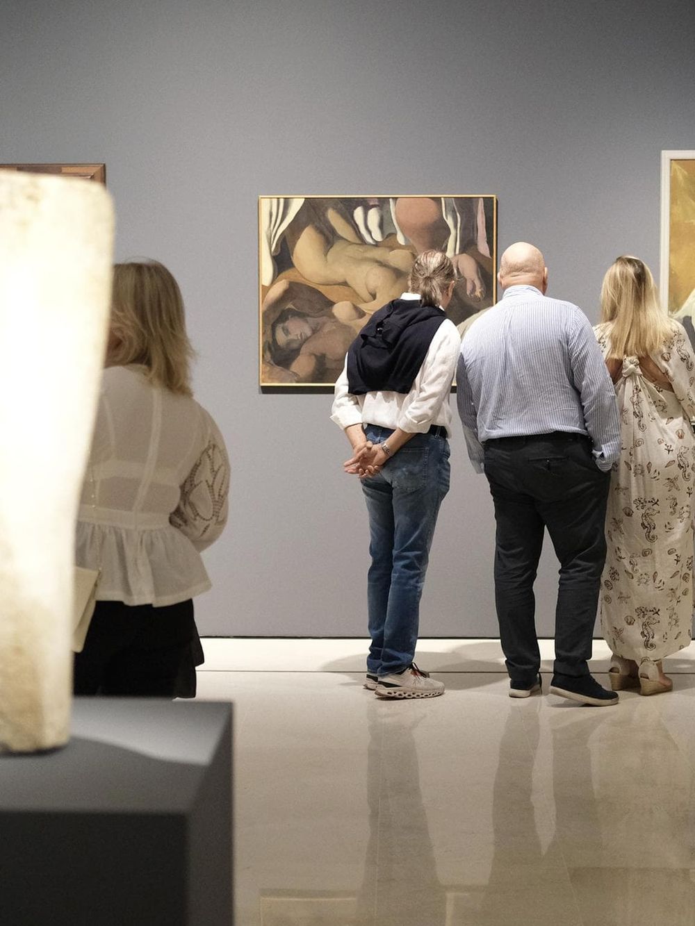 People viewing artwork in an art gallery or museum, exploring diverse paintings and sculptures.