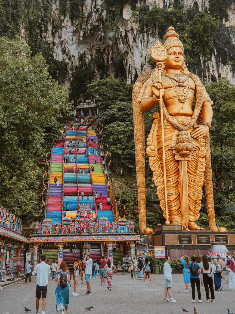 Colorful Batu Caves steps with giant Lord Murugan statue, popular Malaysia tourist attraction.
