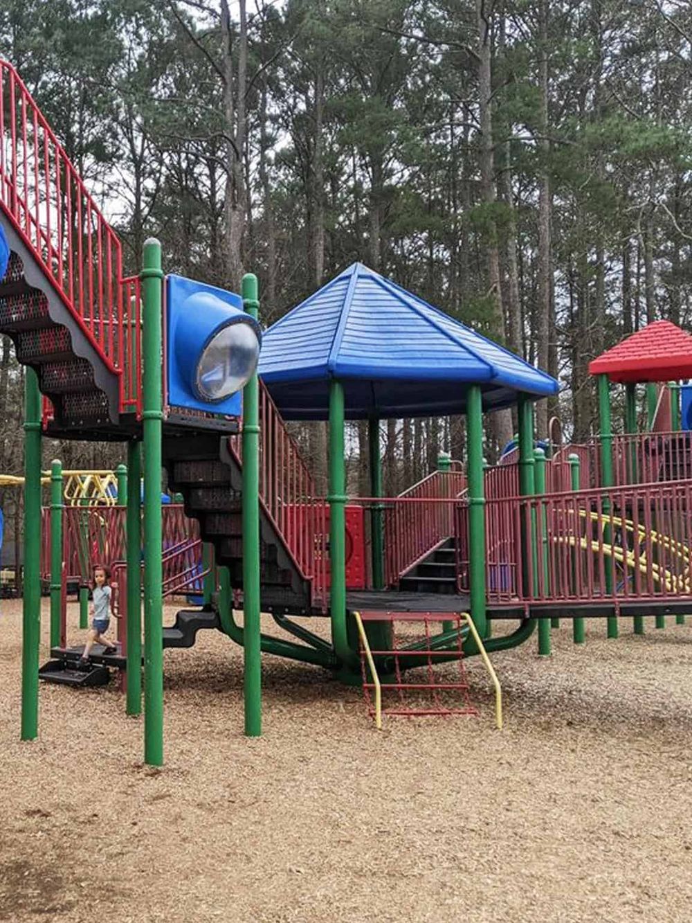 Colorful playground equipment with slides and climbing structures in a park setting.