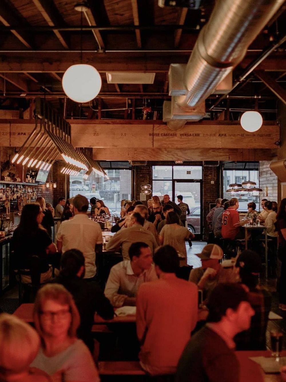 Cozy urban restaurant interior with warm lighting, diverse patrons, and modern-industrial decor, perfect for dining out.