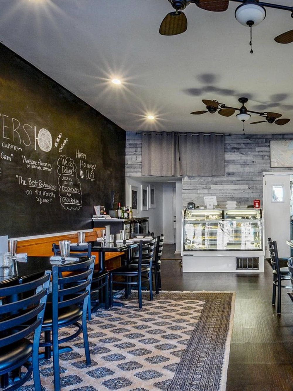 Cozy restaurant interior with black chalkboard wall, wooden accents, seating area, and dessert display, promoting local dining experiences.