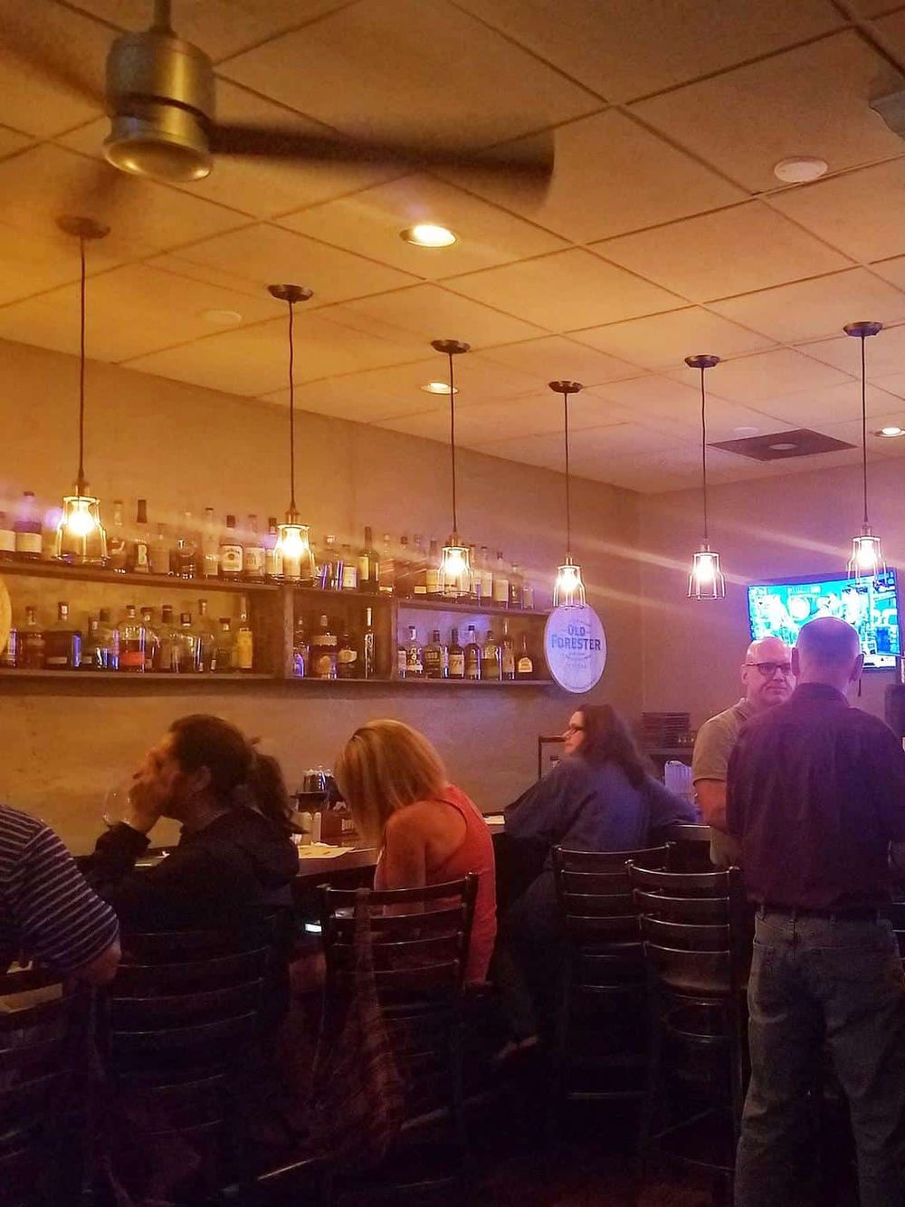 Cozy bar interior with pendant lighting and a variety of bottles on shelves, ideal for social gatherings.