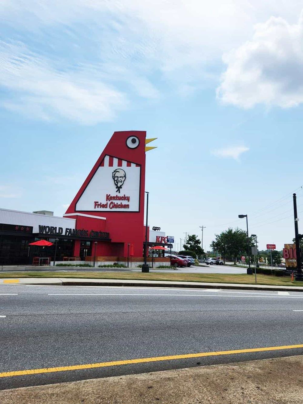 Bright Kentucky Fried Chicken restaurant sign with iconic logo against a blue sky.