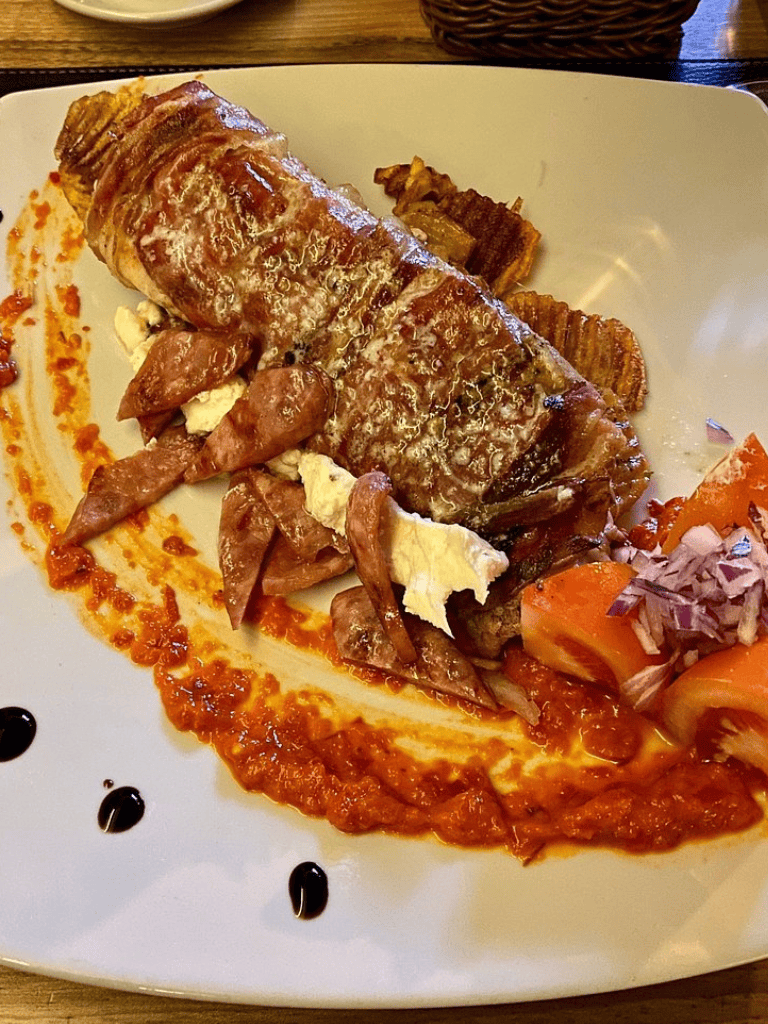 Sausage roll with bacon and salad on white plate, QuestForDirections restaurant cuisine.