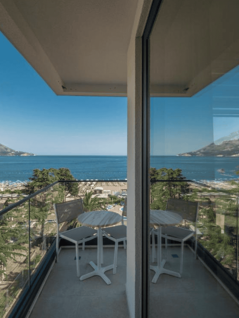 Panoramic ocean view balcony with outdoor seating at QuestForDirections hotel in coastal city.