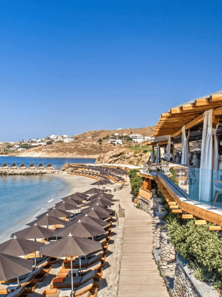 Luxurious beachside resort overlooking the Aegean Sea with sun umbrellas and stunning coastal views.
