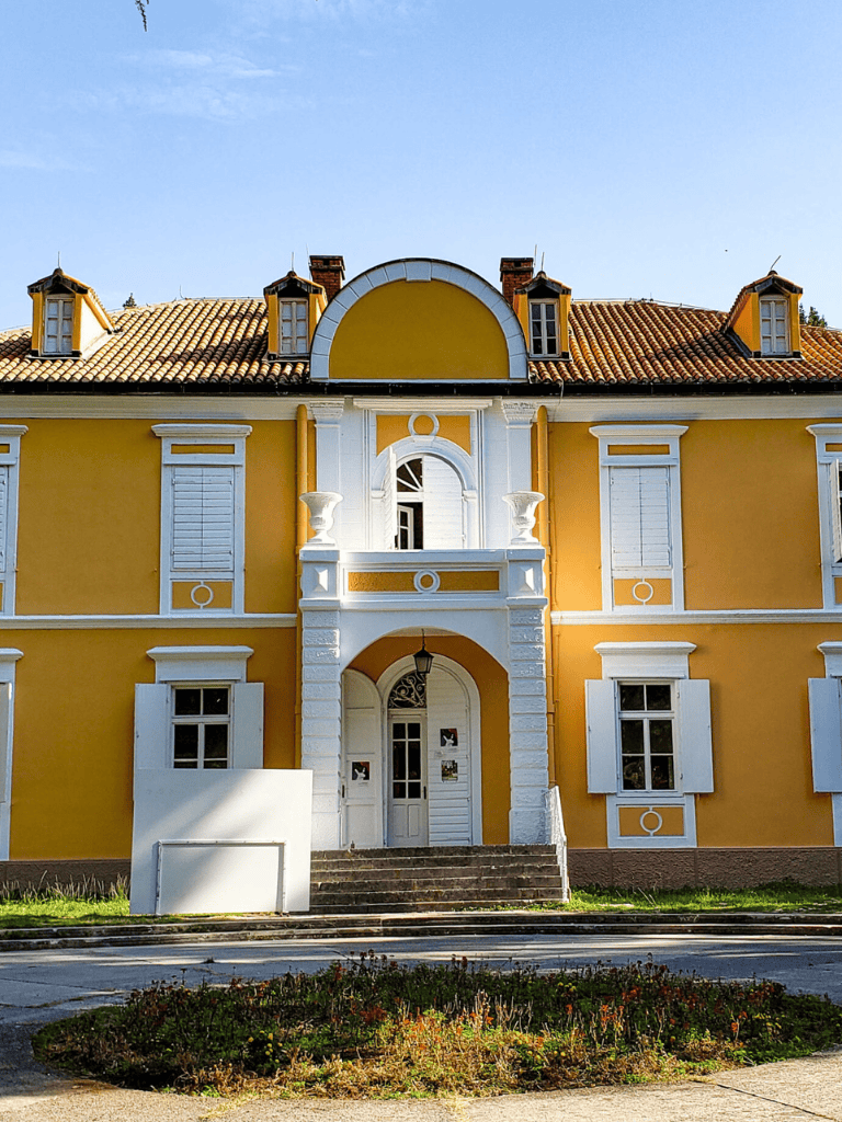 Colorful yellow historic building with white accents, European-style architecture, and a terracotta roof.
