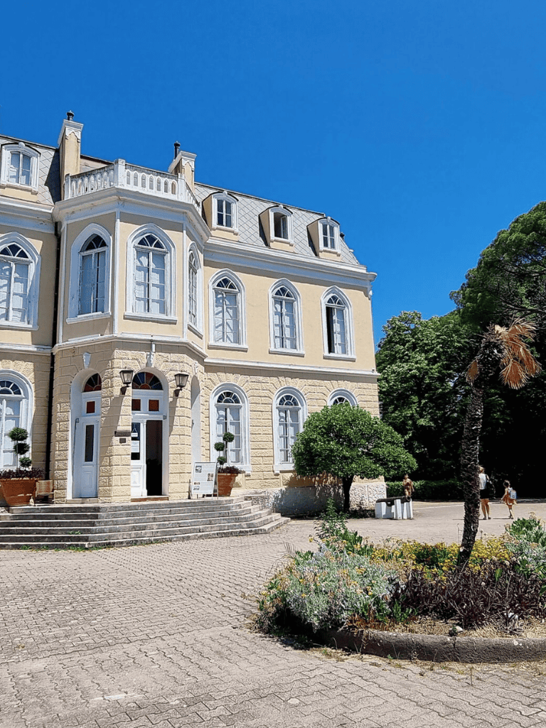 Elegant historic mansion with classic architecture and lush surrounding greenery.