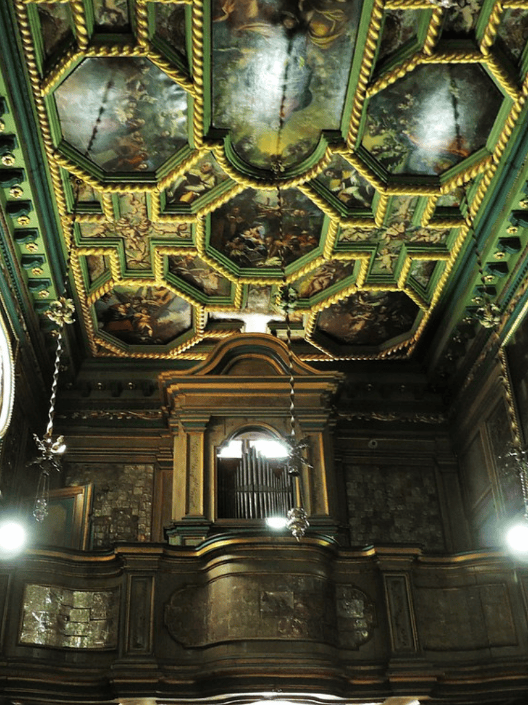 Intricate painted ceiling with gold accents in historic music hall or theater.