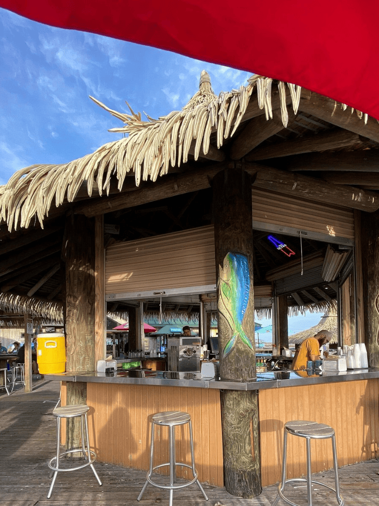 Beachside tiki bar with thatched roof, tropical decor, and ocean views, perfect for relaxed tropical dining.