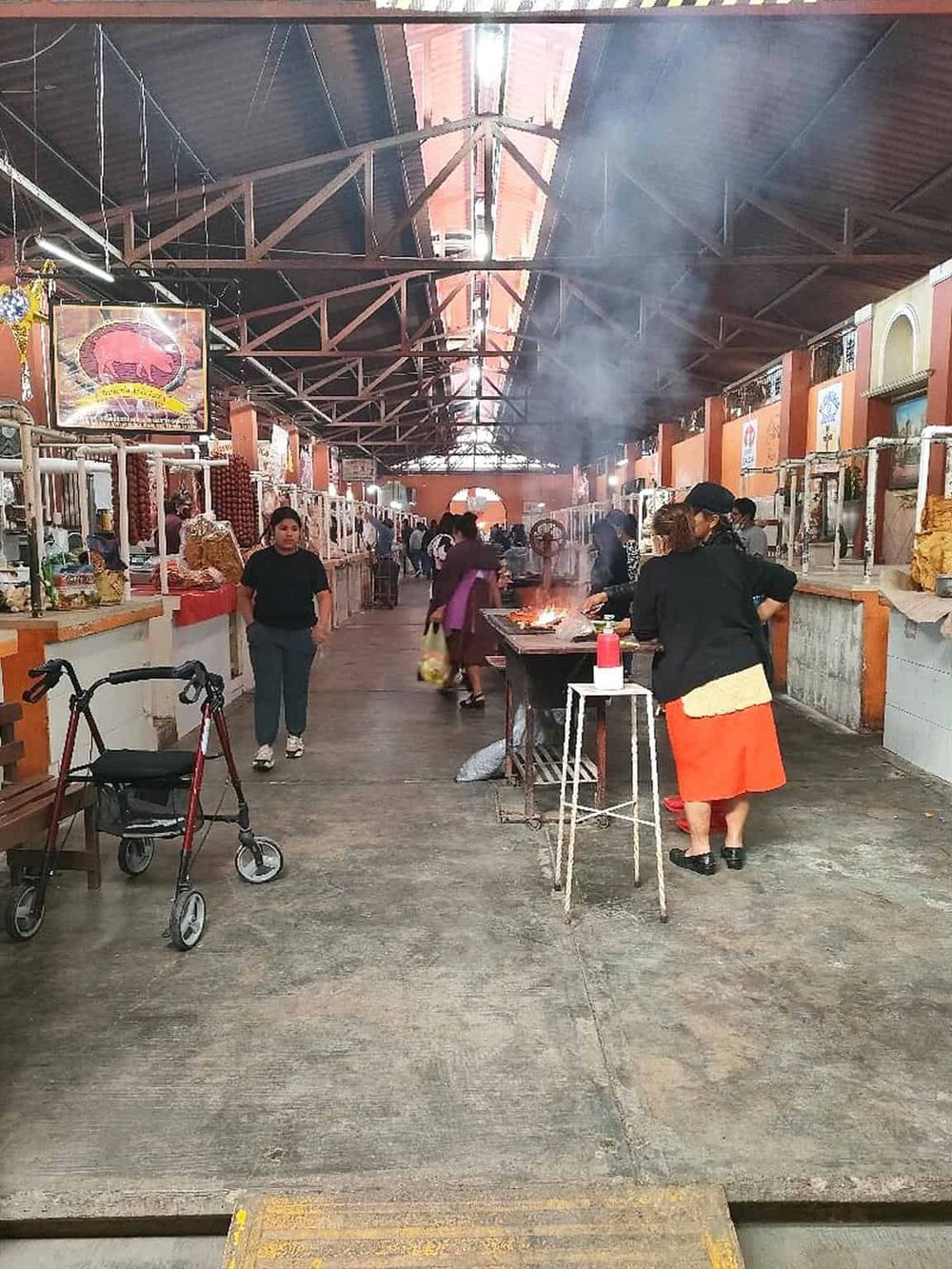 Colorful indoor marketplace with vendors, cooking, and shoppers, showcasing authentic local cuisine and cultural shopping experience.