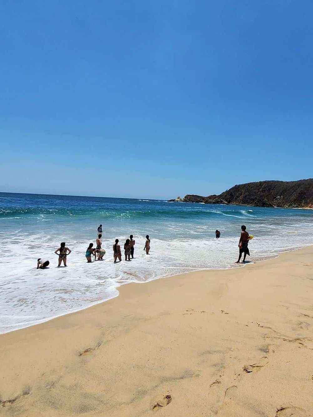 Bright sunny beach scene with children and adults playing and relaxing near the ocean, perfect for family seaside vacation.