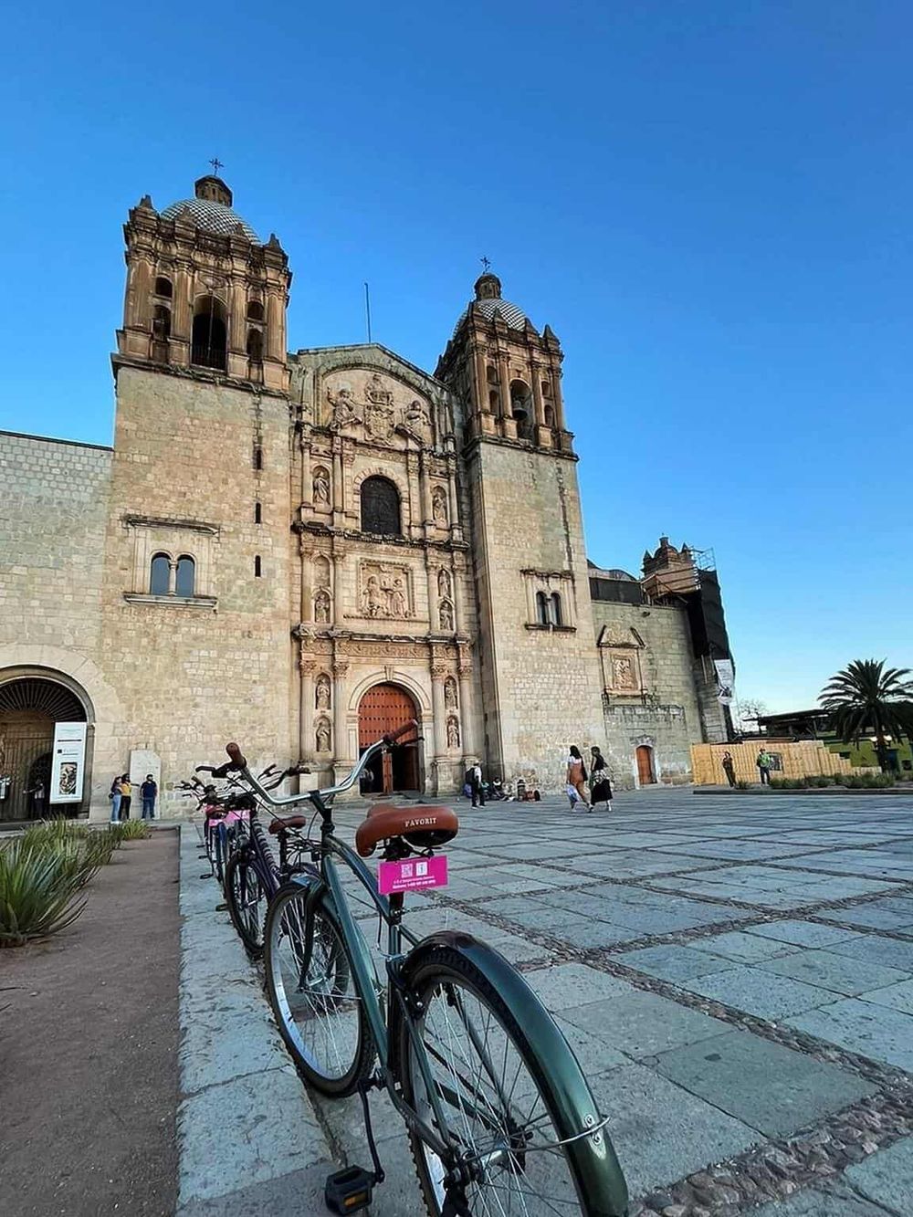 Colorful bicycles parked in front of historic church with stone facade and twin bell towers.