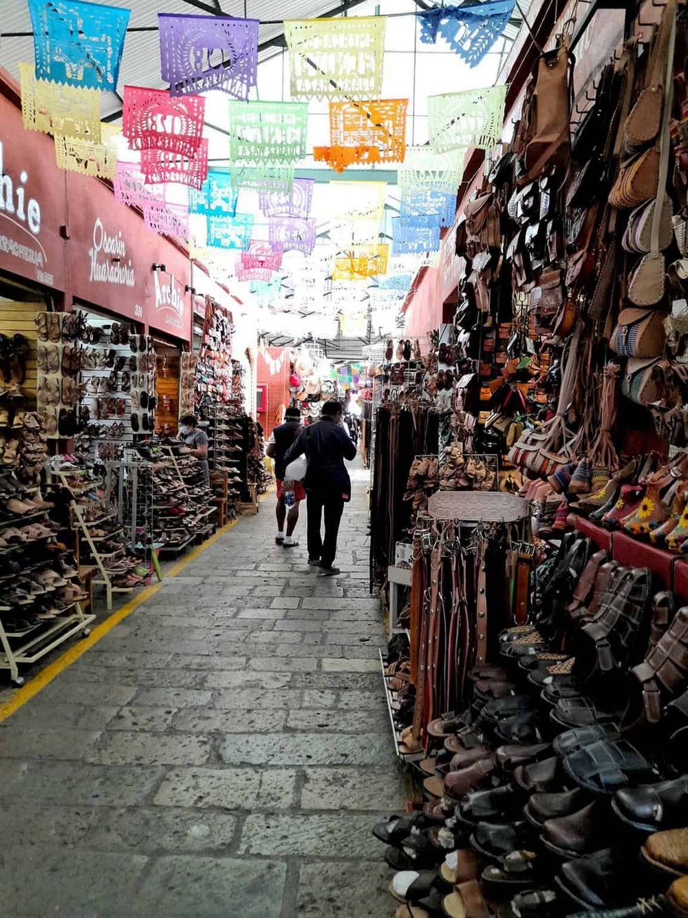 Colorful papel picado decorations hanging in a lively outdoor shoe market.