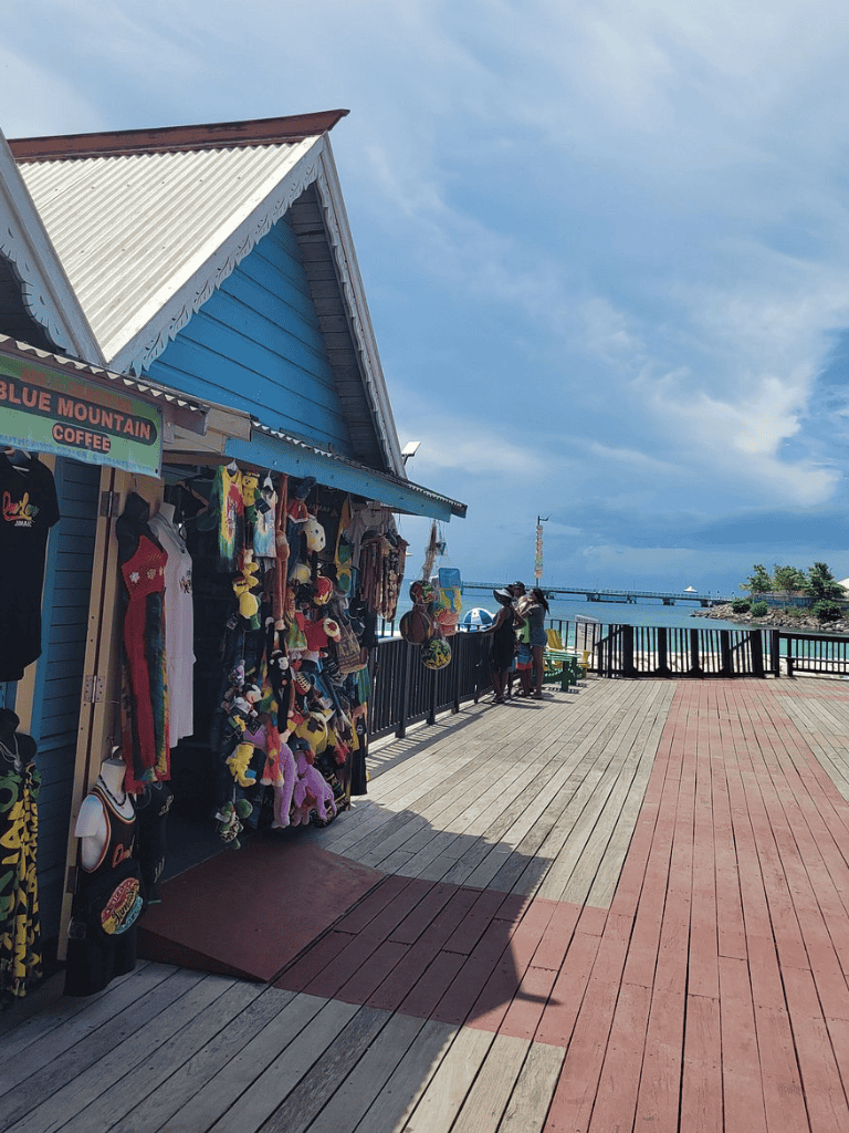 Colorful souvenir shop on a pier with ocean view and blue sky, perfect for travel shopping and coastal adventure — QuestForDirections.