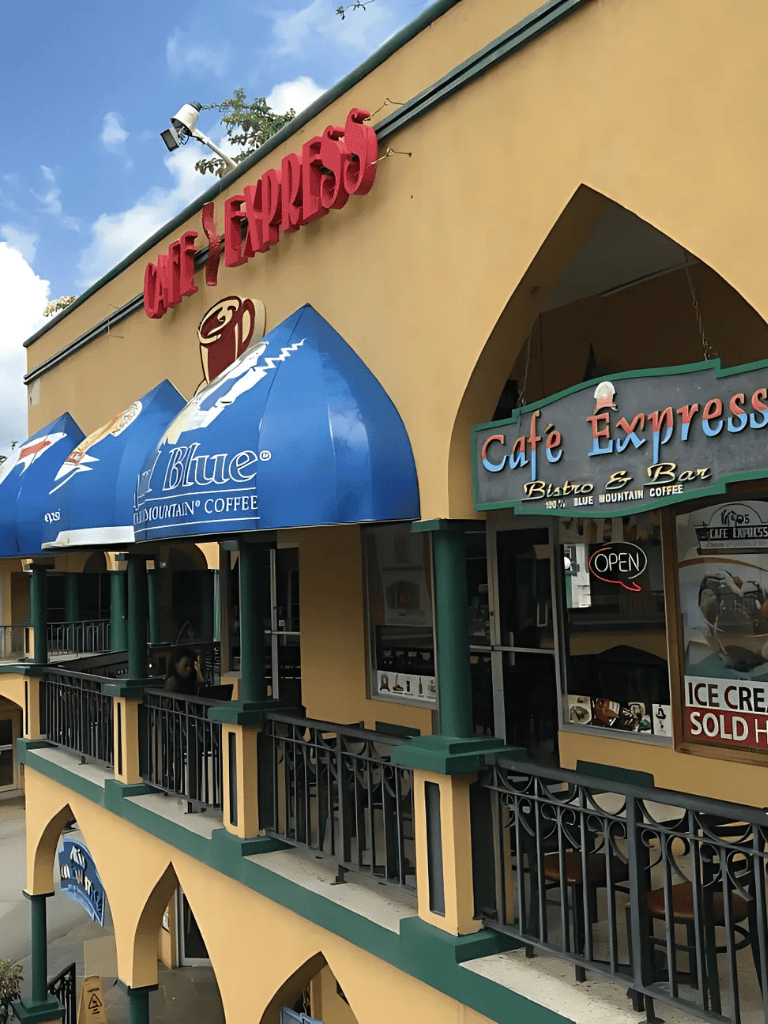 Coffee shop façade with signage for Cafe Express and Blue Mountain Coffee, blue awnings, and outdoor seating area.