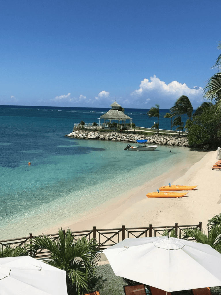 Serene tropical beach with turquoise waters, palm trees, and a gazebo on the pier, perfect for relaxing vacations and seaside getaways.