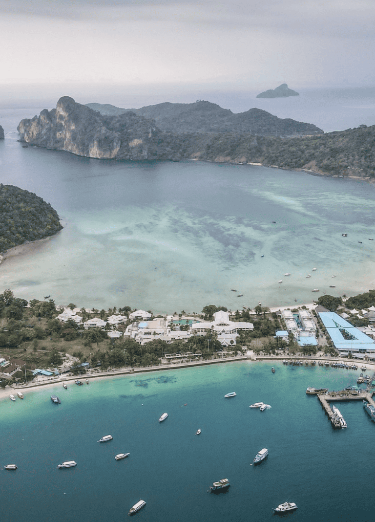 Aerial view of tropical island with turquoise waters, boats, and lush greenery, perfect for travel and adventure.