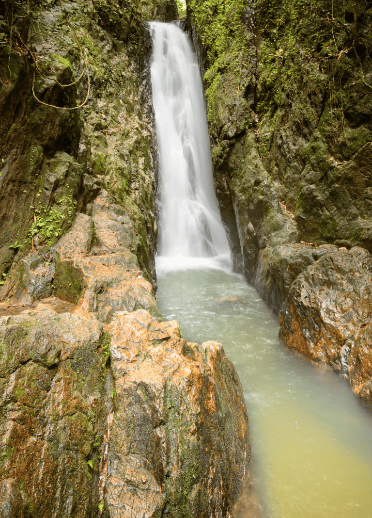Serene waterfall in lush forest with moss-covered rocks, nature, tranquility, and scenic outdoor landscape.