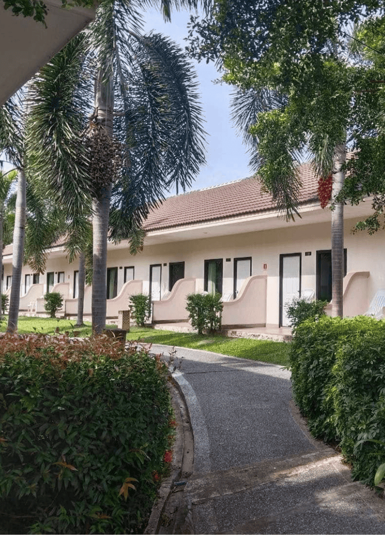 Cozy motel room with lush green landscaping and tropical trees, perfect for relaxing getaways.