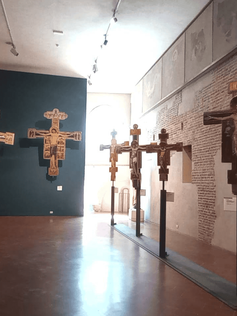Intricately carved wooden crosses displayed in a museum exhibit, showcasing religious art and history artifacts.