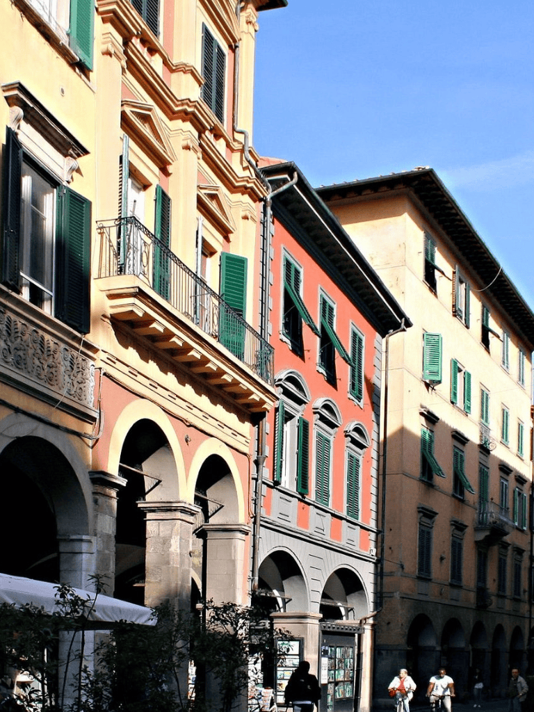 Colorful historic buildings along a sunny street in Italy, showcasing European architecture and vibrant city life.