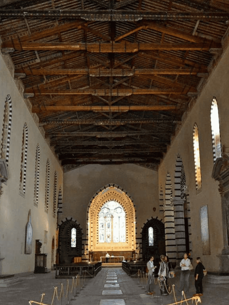 Serene interior of a historic church with large stained glass windows and wooden ceiling, inviting visitors to explore architectural beauty.