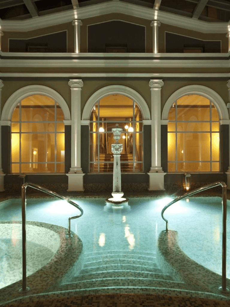 Elegant indoor pool area with classic architecture and ambient lighting, perfect for relaxation and wellness.
