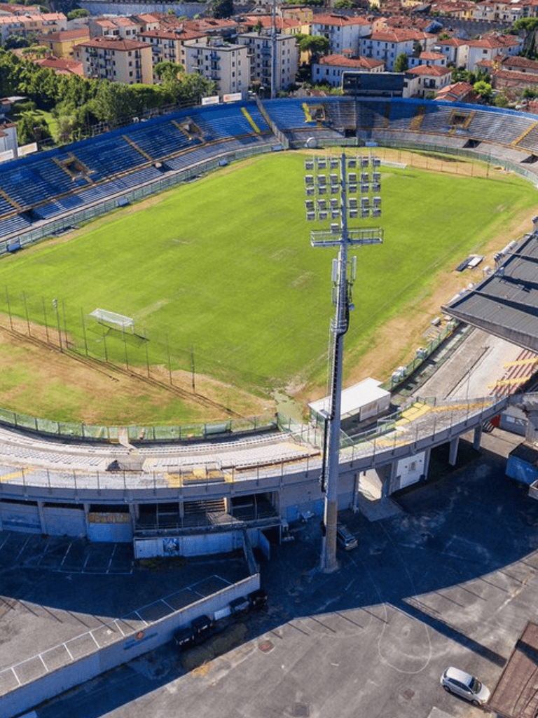 Aerial view of a soccer stadium with green field and surrounding tracks, in an urban area.